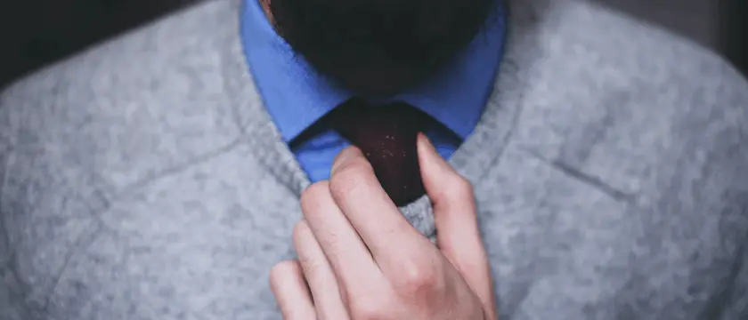 Bearded man adjusting his tie.